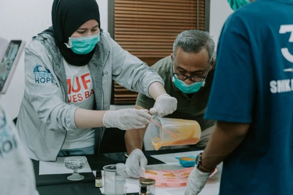Peserta dan fasilitator bekerja bersama dalam proses pembuatan sabun.